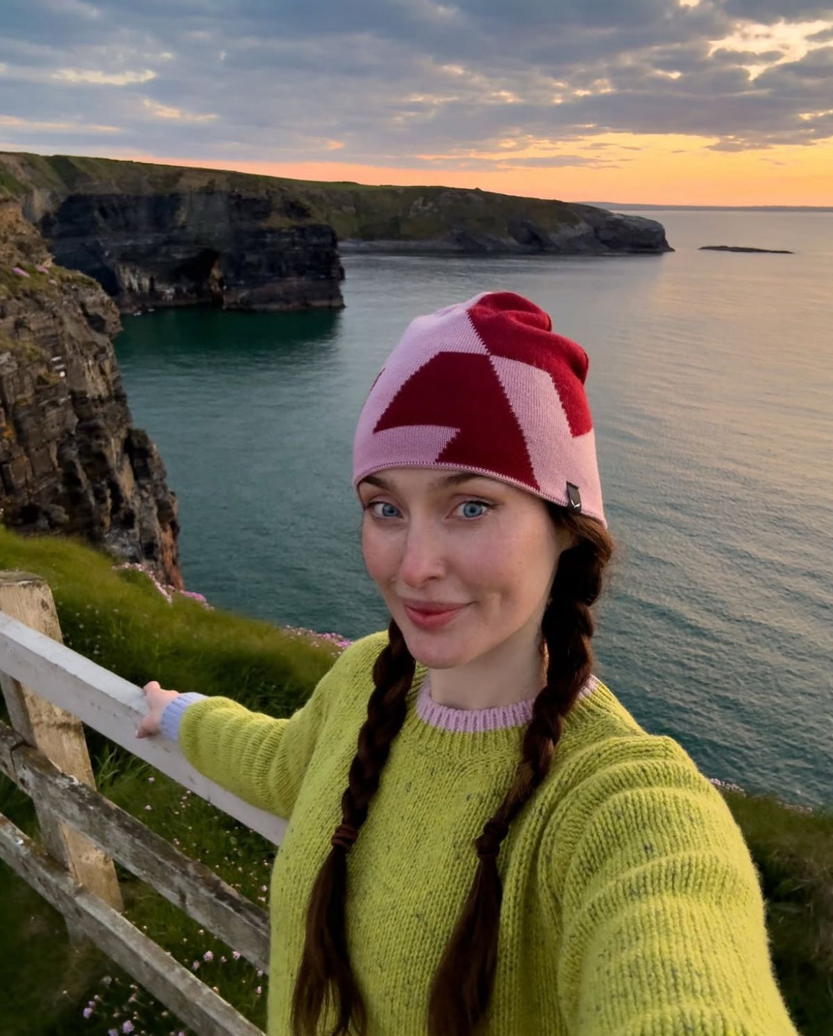 Roz Purcell posing in from of the Cliffs of Moher wearing her Aoife Mc Namara Wild Meadows Green Jumper 