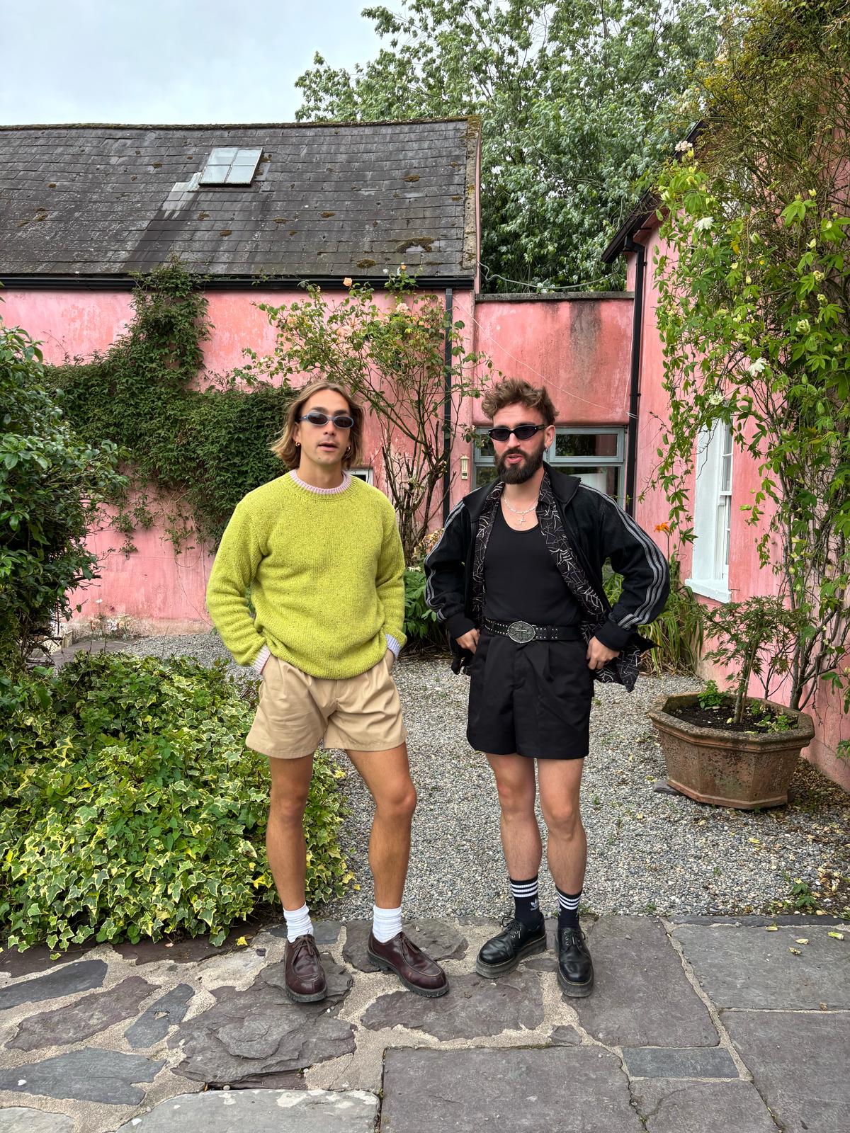 Rob de Boer casually poses in front of a pink house wearing his Aoife Mc Namara Wild Meadows Green Jumper